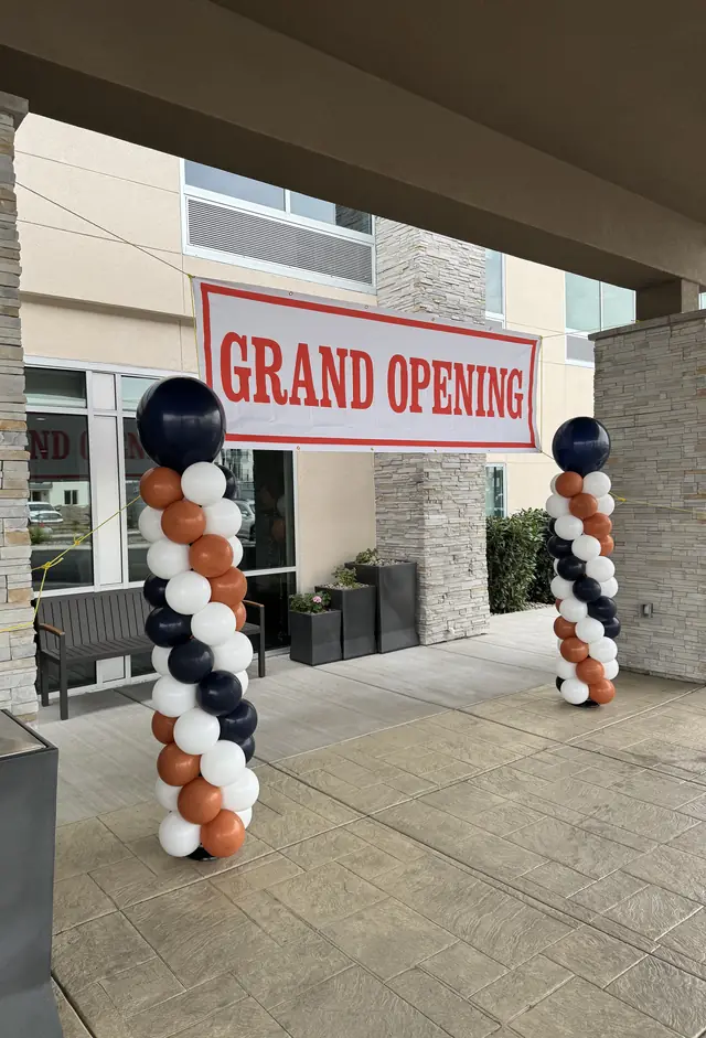 Navy, orange, and white balloon columns framing a Grand Opening banner at a hotel entrance